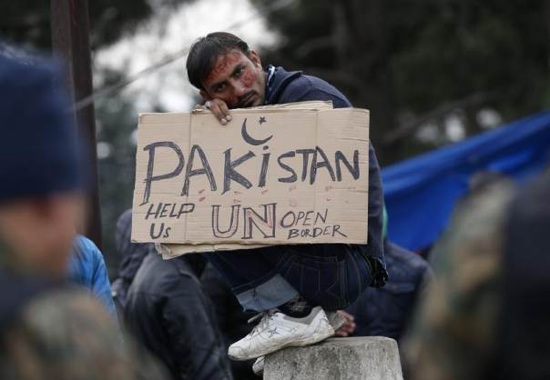 A migrant from Pakistan holds a placard while waiting to cross the border from Greece into Macedonia, near Gevgelija, Macedonia November 26, 2015. PHOTO: REUTERS