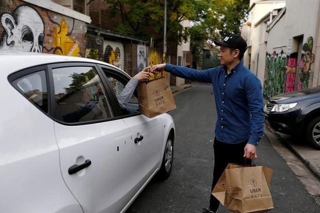 An Uber driver takes delivery of bags of donuts destined for a customer via Uber Eats in Sydney.PHOTO: REUTERS