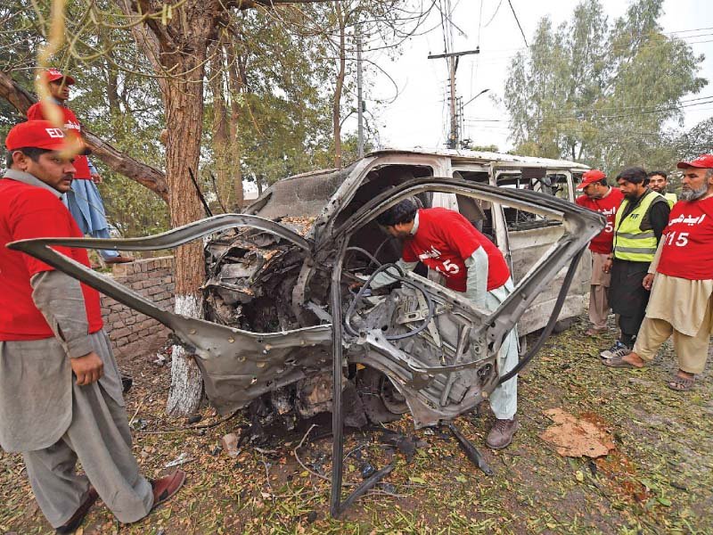Volunteers inspect the mangled heap of a van targeted in the Peshawar suicide attack. A photo of the three Levies men killed in the Mohmand bombings. PHOTO: AFP/EXPRESS