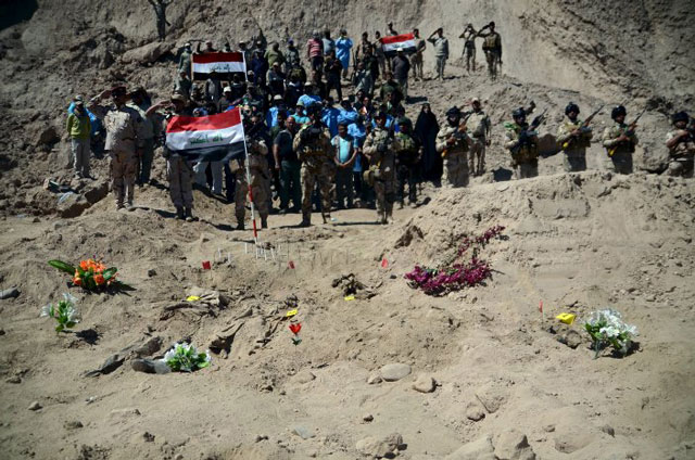 Iraqi soldiers salute as they stand next to a mass grave for Shia soldiers from Camp Speicher who have been killed by Islamic State militants in the presidential compound of the former Iraqi president Saddam Hussein in Tikrit April 6, 2015. PHOTO: REUTERS