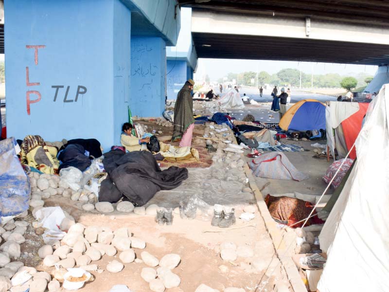 Protesters rest ready to pelt stones at police. PHOTO: MUDASSAR RAJA/EXPRESS