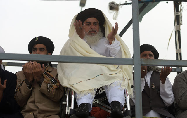 Head of the Tehreek-i-Labaik Yah Rasool Allah Pakistan (TLYRAP) Khadim Hussain Rizvi (C), offers Friday prayers on a blocked flyover bridge during a protest in Islamabad on November 24, 2017. PHOTO: AFP