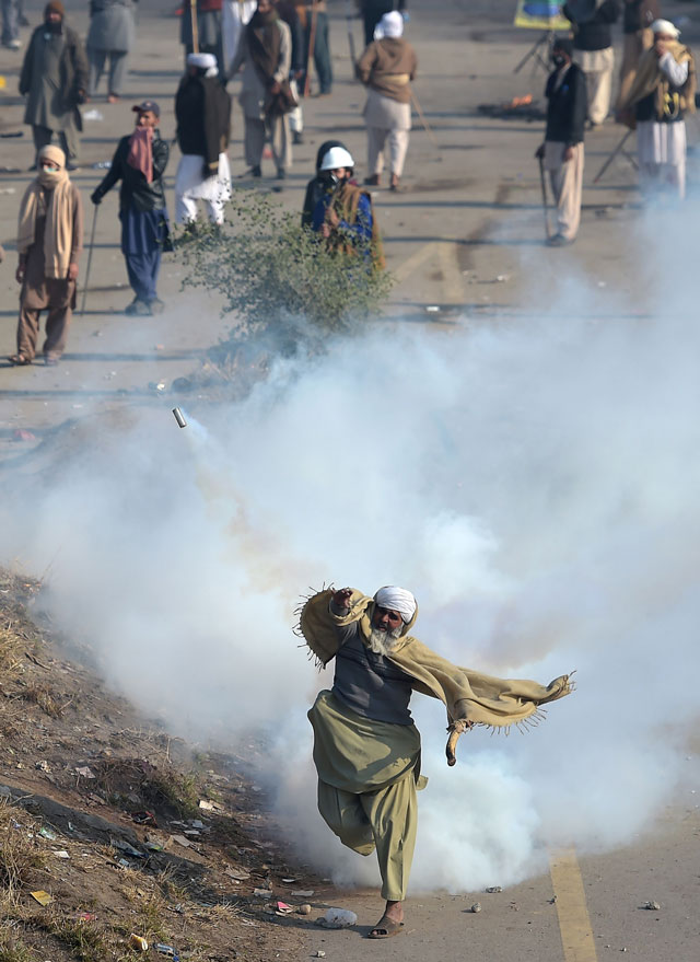 A protester of the Tehreeke Labaik throws a tear gas shell back towards police during a clash in Islamabad on November 25, 2017. PHOTO: AFP
