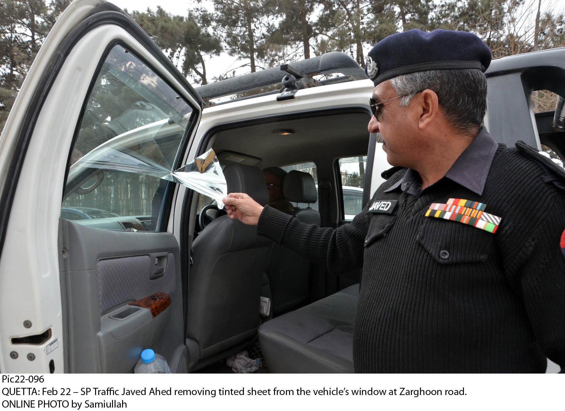 Traffic Superintendent of Police Javed Ahad removing tint from a vehicle's window on Zarghoon Road in Quetta. PHOTO: ONLINE