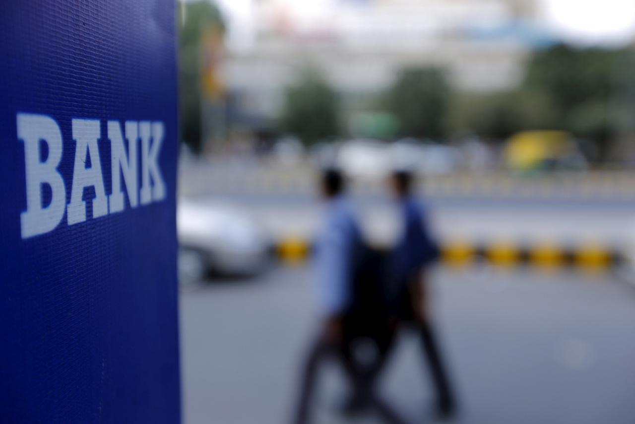 Commuters walk past a bank sign along a road. PHOTO: REUTERS