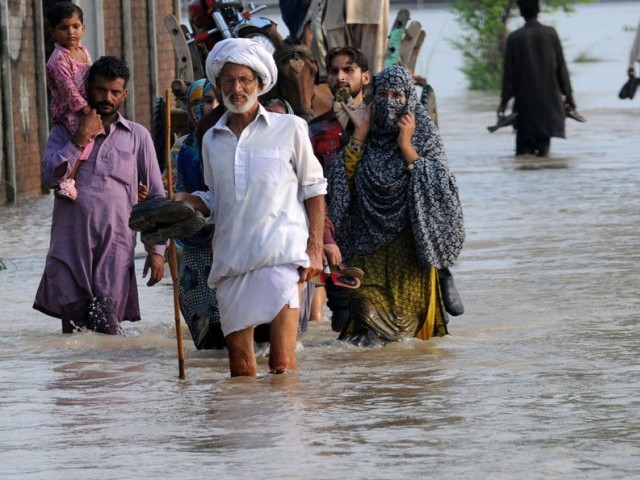 In this file photo, flood affected villagers walk through water in Murredke. PHOTO: AFP