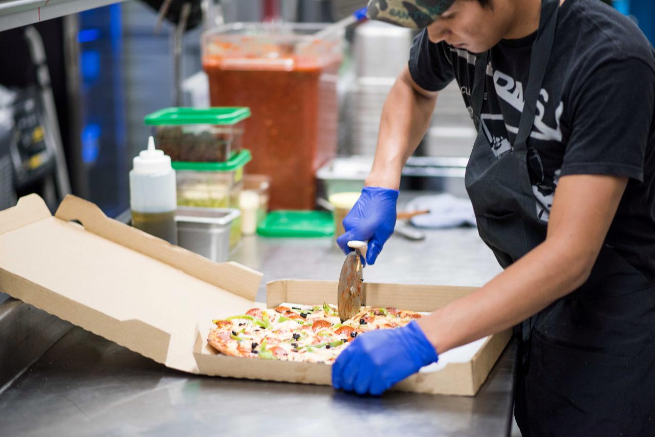 A kitchen staffer a pizzeria prepares a pizza for delivery. PHOTO: REUTERS