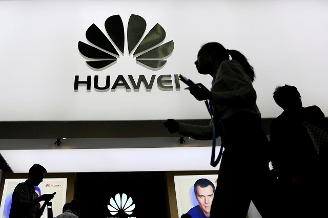FILE PHOTO: People walk past a sign board of Huawei at CES (Consumer Electronics Show) Asia 2016 in Shanghai, China May 12, 2016. PHOTO: REUTERS