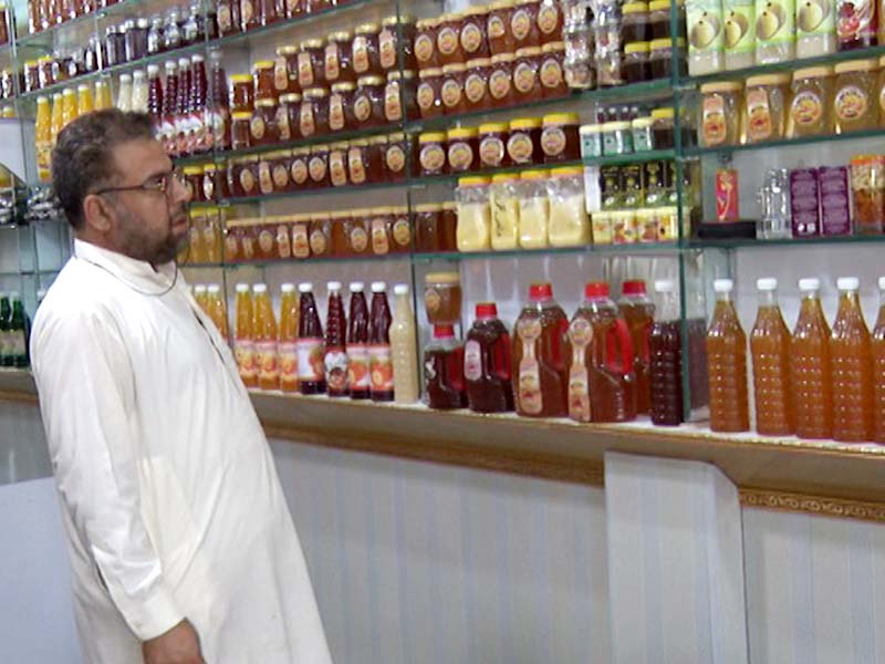 A customer looks at a large variety of honey bottles at a shop that also sells whole beehives in Peshawar . PHOTOS: EXPRESS
