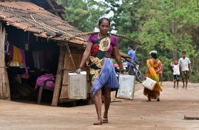 An Indian woman carries water in stainless steel cans at Shakar Pada village near Shahapur, on the outskirts of Mumba. PHOTO: AFP