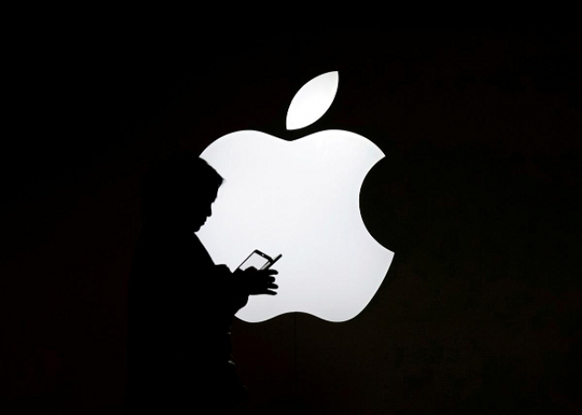 A woman looks at the screen of her mobile phone in front of an Apple logo outside its store in Shanghai, China July 30, 2017. PHOTO: REUTERS