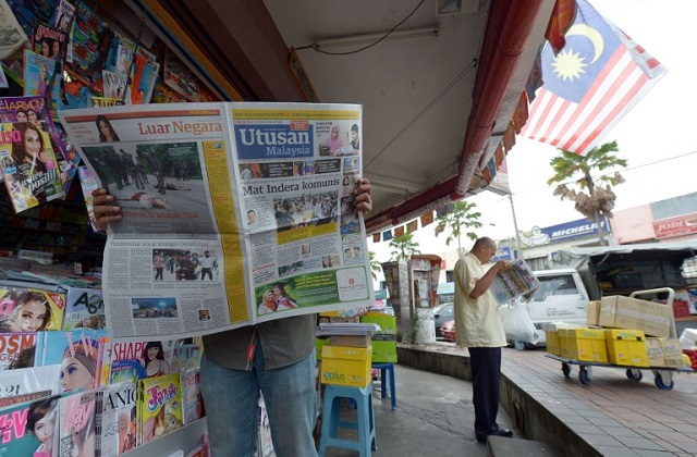 A Malaysian man reads a newspaper outside a shop in downtown Kuala Lumpur on October 10, 2012. PHOTO: AFP