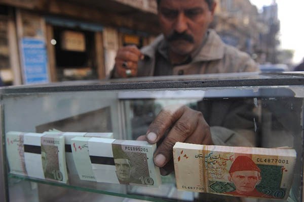 A vendor arranges 10 and 20-rupee Pakistani bank notes in a display shelf at a commercial area in Karachi. PHOTO: AFP