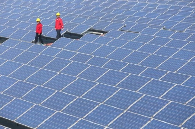 Workers walk past solar panels in Jimo, Shandong Province, China, April 21, 2016. PHOTO: REUTERS