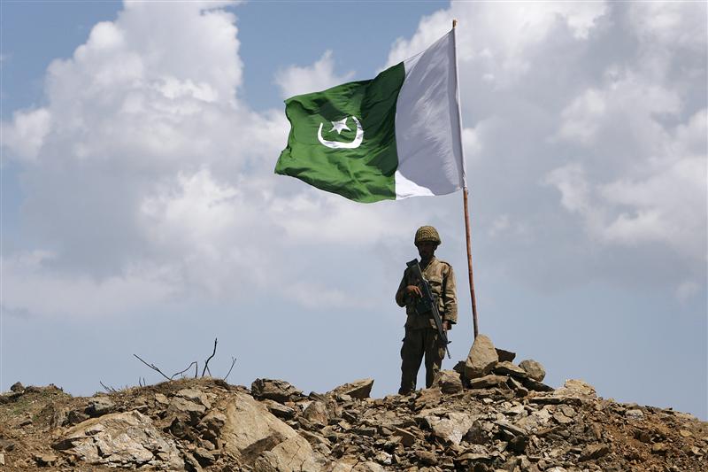 A Pakistani soldier poses for a photo under Pakistan's national flag planted atop the Baine Baba Ziarat mountain in Swat district. PHOTO: REUTERS