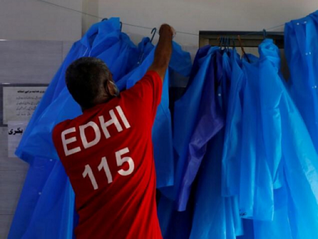 A volunteer of the Edhi Foundation, a non-profit social welfare programme, hangs up raincoats to be used to handle suspected carriers of the coronavirus disease (COVID-19), in Karachi, Pakistan March 26, 2020. PHOTO: REUTERS