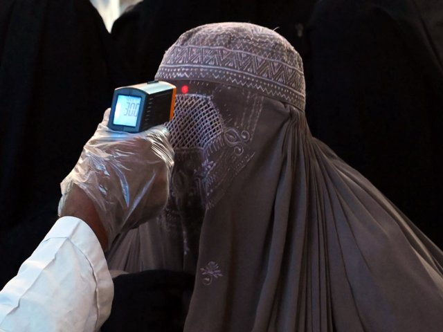 A health worker checks the body temperature of a burqa-clad woman passenger amid concerns over the spread of the novel coronavirus at the railway station in Lahore. PHOTO: AFP/FILE