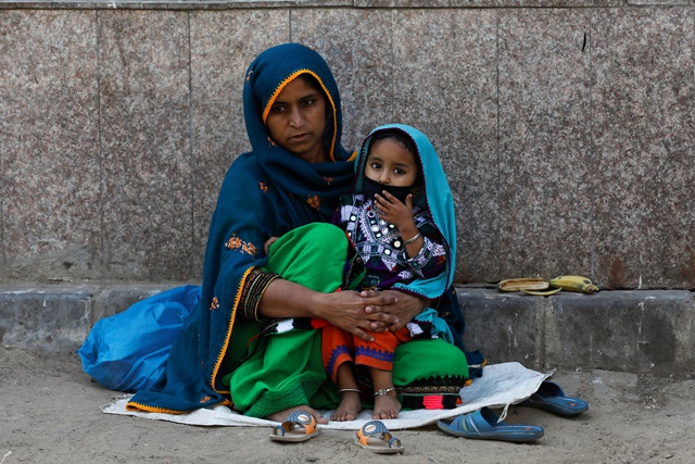 Three-year-old Nadia wears protective mask sitting on her mother's lap, as they are waiting to visit an ailing family member, outside a hospital during a lockdown after Pakistan shut all markets, public places and discouraged large gatherings amid an outbreak of coronavirus disease (COVID-19), in Karachi, Pakistan, April 1, 2020. REUTERS/Akhtar Soomro