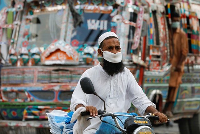 A man wearing a protective face mask rides a motorbike, as the outbreak of the coronavirus disease (COVID-19) continues, in Karachi, Pakistan June 11, 2020. REUTERS