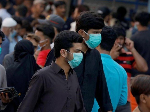 Men wearing protective face masks walk amid the rush of people outside a market as the outbreak of the coronavirus disease (Covid-19) continues, in Karachi. PHOTO: REUTERS/FILE