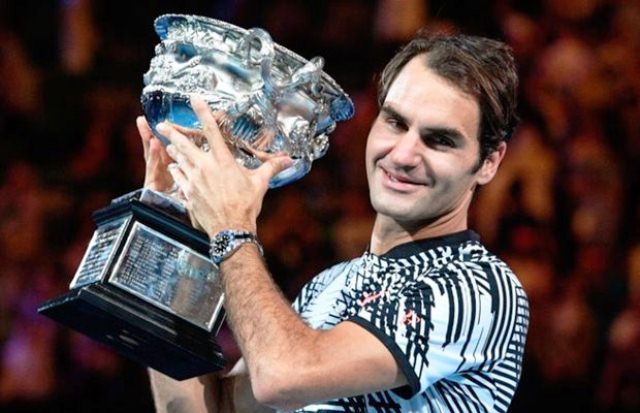 Switzerland's Roger Federer celebrates with the championship trophy during the awards ceremony after his victory against Spain's Rafael Nadal in the men's singles final of the Australian Open in Melbourne on January 29, 2017 PHOTO: AFP/WILLIAM WEST