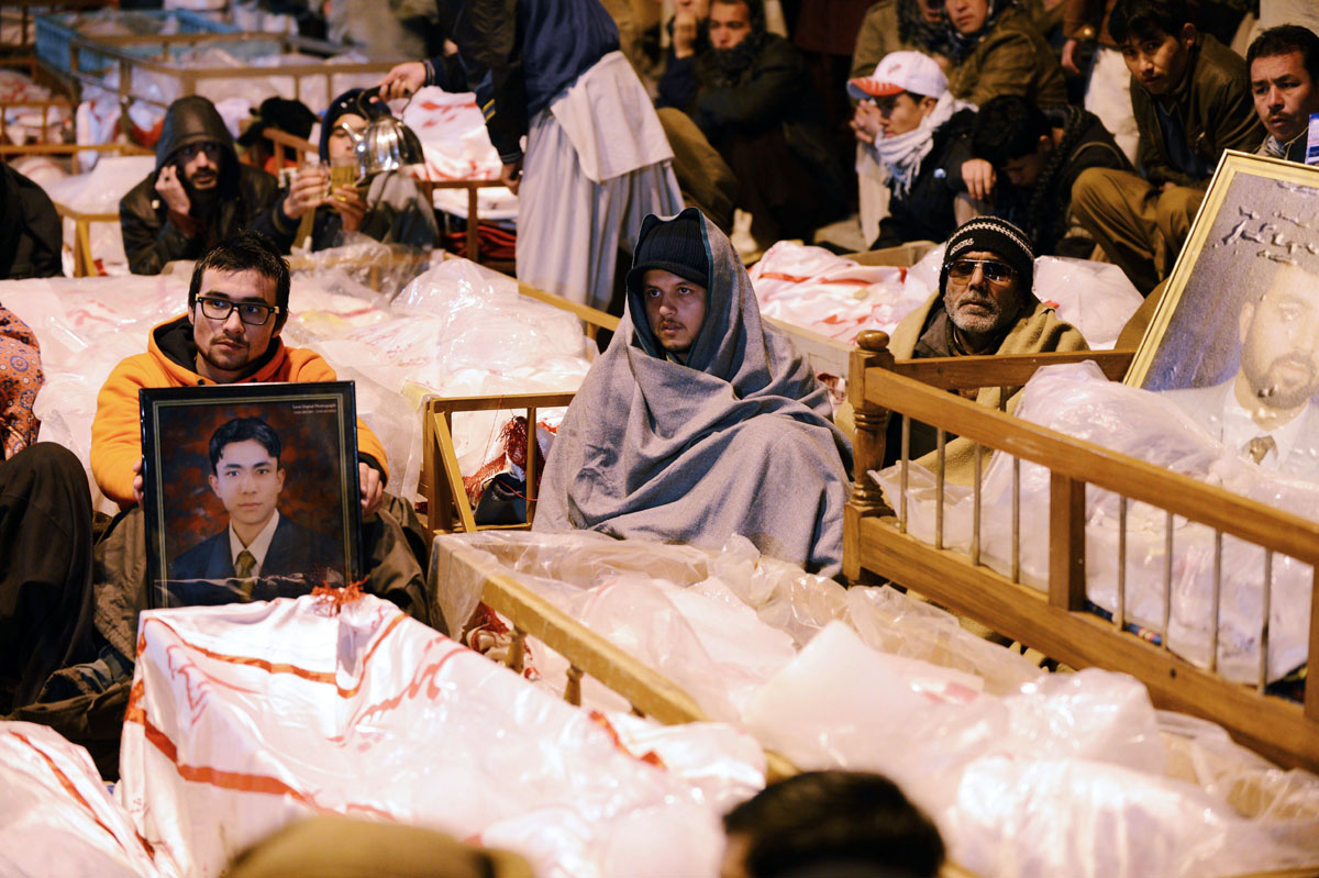 Shia Muslims demonstrate and sit amongst the coffins and portraits of bomb blast victims in Quetta on January 12, 2013. PHOTO: AFP