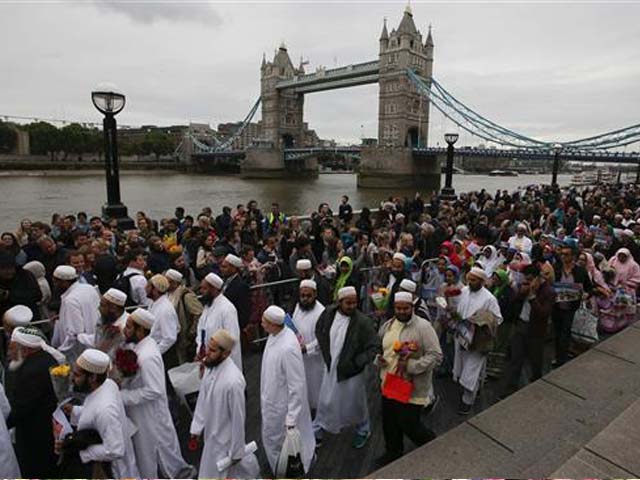 Members of the Dawoodi Bohra Muslim community (in white) join others as they bow their heads during a vigil at Potters Fields Park in London on June 5, 2017 to commemorate the victims of the terror attack on London Bridge and at Borough Market that killed seven people on June 3. PHOTO: AFP