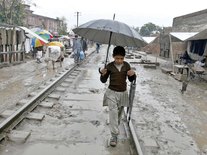 A child treading Hashtnagri Railway tracks. Peshawar received more than 15 millimetres of rain. PHOTO: PPI