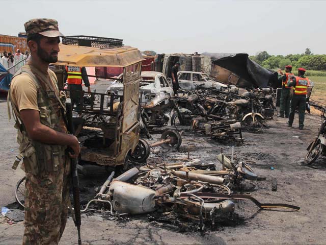 Pakistani soldiers stand guard beside burnt out vehicles at the scene where an oil tanker caught fire following an accident on a highway near the town of Ahmedpur East, some 670 kms (416 miles) from Islamabad on June 25, 2017.
At least 123 people were killed and scores injured in an inferno that erupted after an oil tanker overturned in central Pakistan early on June 25 and crowds rushed to collect fuel, an official said. PHOTO: AFP / SS MIRZA