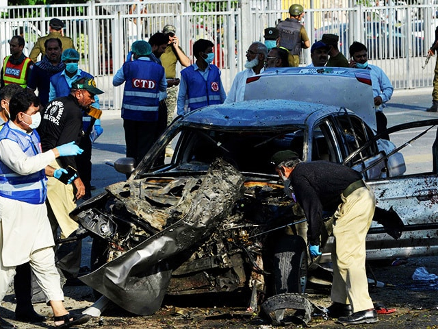 Security officials inspect a destroyed vehicle after an explosion in Lahore. PHOTO: AFP