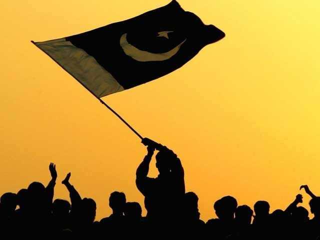 A man waves the flag of Pakistan in the air as people watch the ceremony to lower the national flags at the border crossing between Pakistan and India March 11, 2004 in Wagah, Pakistan. PHOTO: GETTY