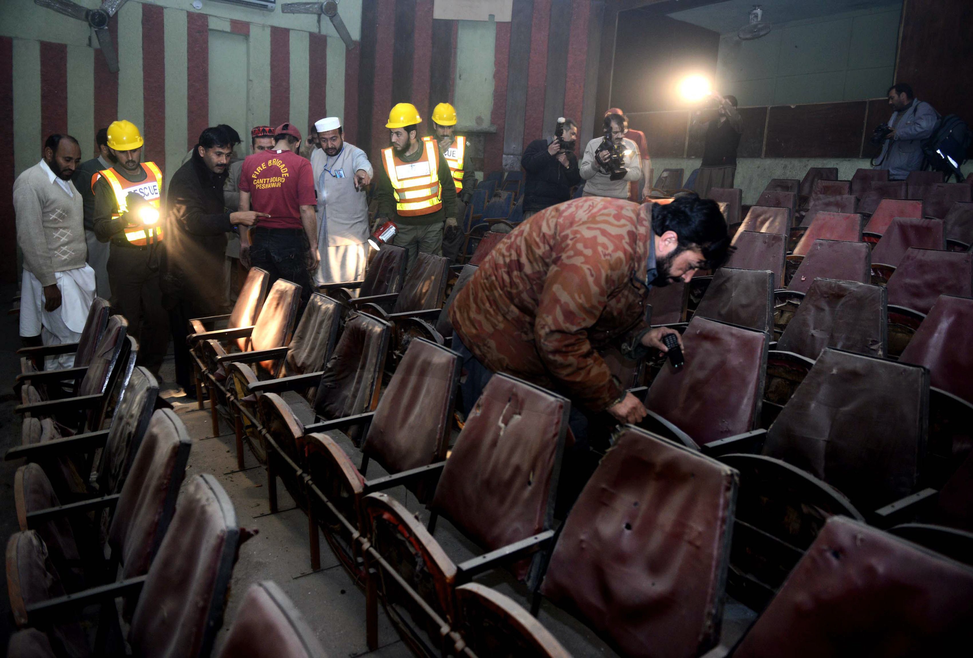 Volunteers and security officials investigate the cinema after the attack. PHOTO: AFP