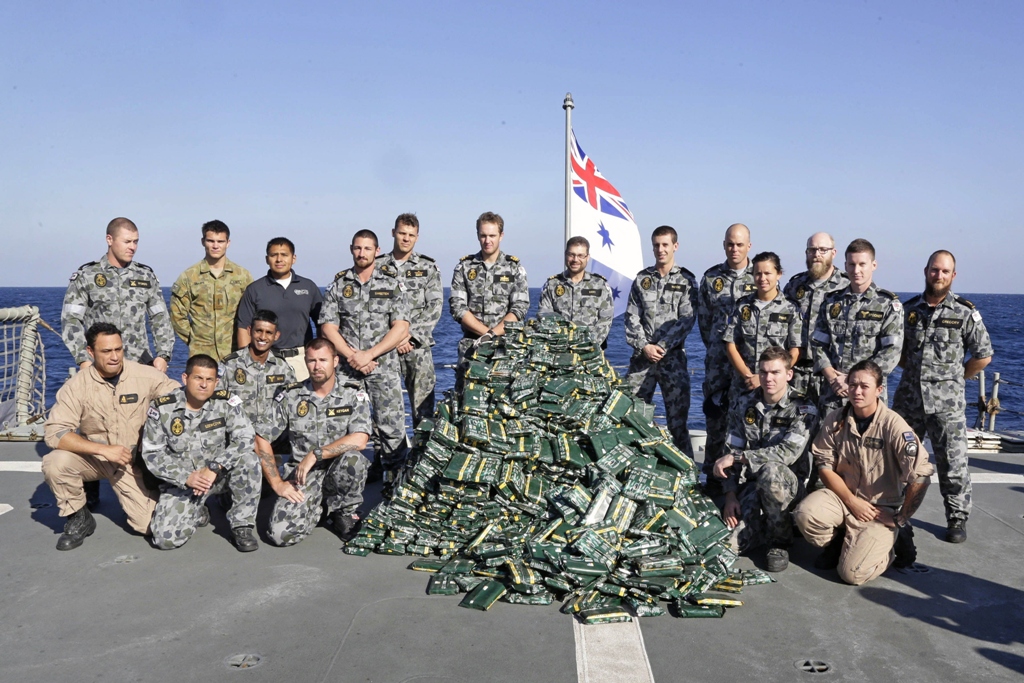 A handout photo released on February 18, 2014 by the Australian Government Department of Defence shows HMAS Melbourne's boarding party gathering around nearly two tonnes of hashish piled up on the ship's flight deck following a successful narcotics inderdiction operation in the Middle East Area of Operations. PHOTO: AFP