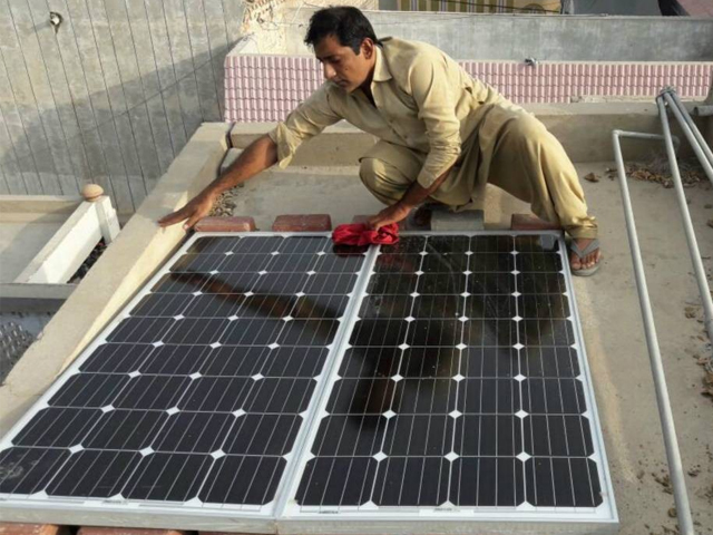 A man wipes the dust off solar panels he recently installed on the roof of his home in Larkana, in Pakistan’s Sindh province, June 28, 2017. PHOTO: REUTERS