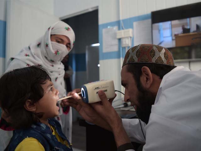 A Pakistani paramedic checks a child's throat at a telemedicine online treatment centre. PHOTO: AFP