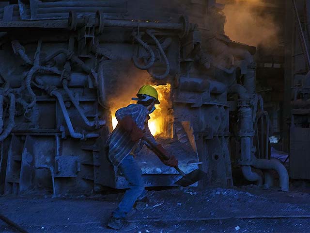 An employee shovels coal into a furnace used for smelting iron inside a steel plant in Karachi. PHOTO: GETTY
