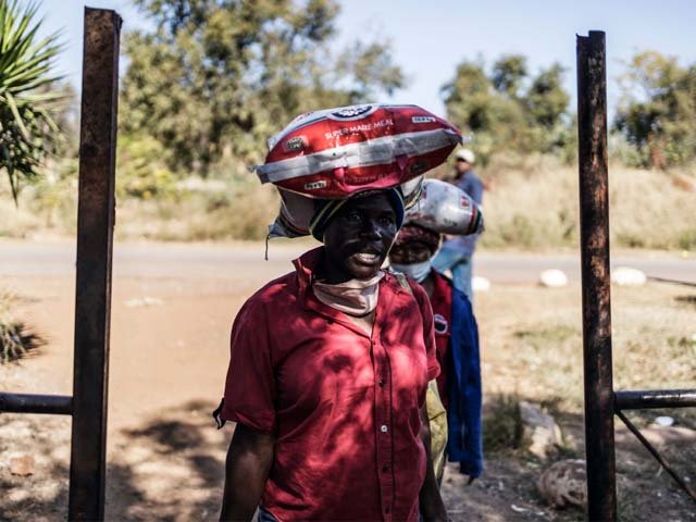 Residents of an informal settlement in Pretoria, leave with bags of food following a food distribution drive. PHOTO: AFP