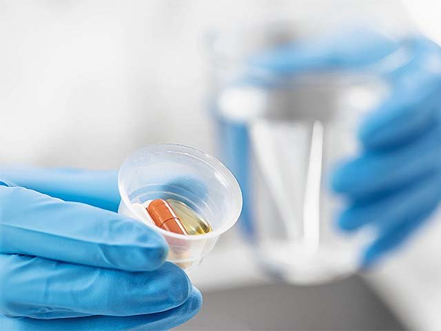 A doctor holding a graduated medicine cup full of pills. PHOTO: AFP