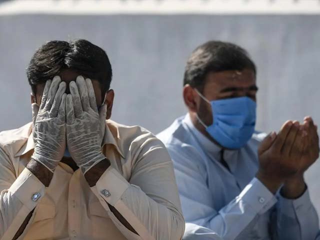 A man wearing a facemask and hand gloves offers prayers in Rawalpindi. PHOTO: AFP